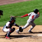 A catcher is poised to catch a ball while the batter swings.