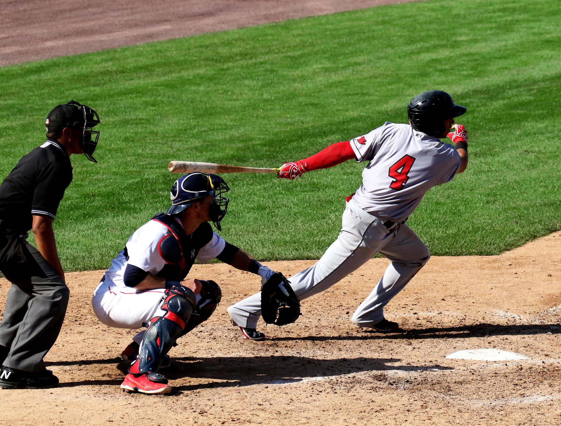 A catcher is poised to catch a ball while the batter swings.