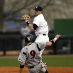 A runner slides into base as the infielder catches the ball.