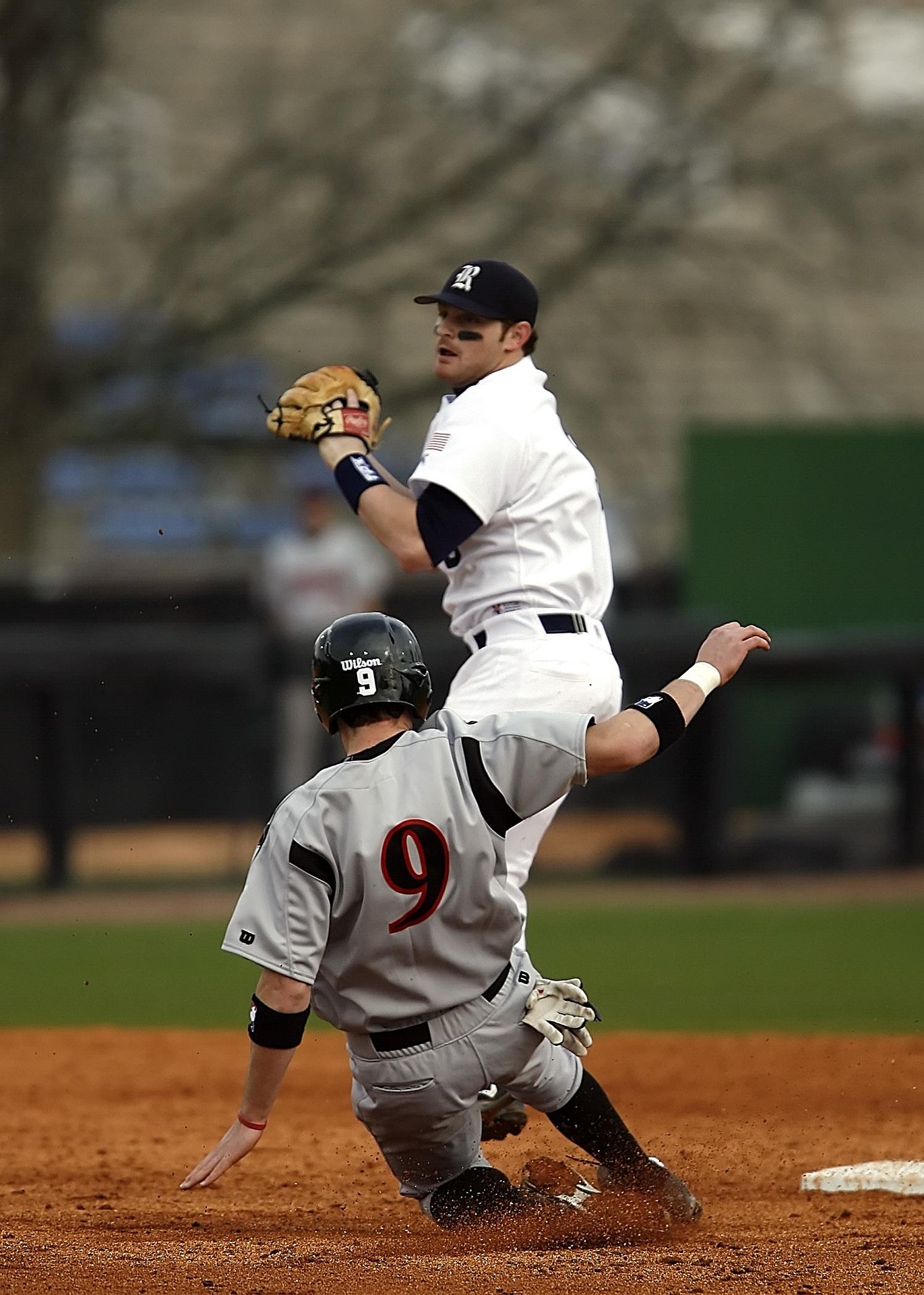 A runner slides into base as the infielder catches the ball.