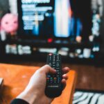 A person holds the TV remote and looks for something to watch.