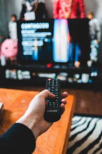 A person holds the TV remote and looks for something to watch.