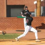 A baseball player follows through on a swing.