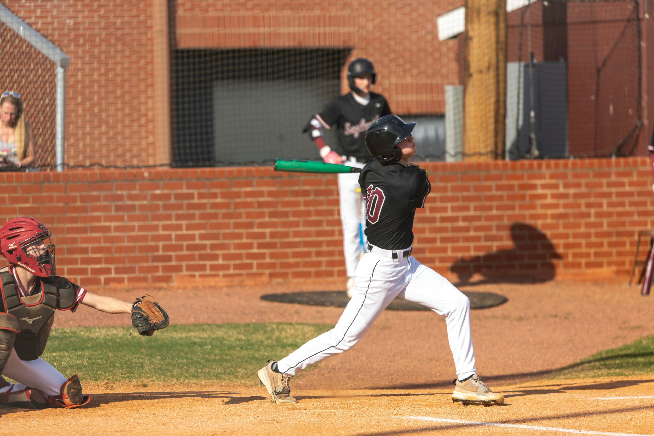 A baseball player follows through on a swing.