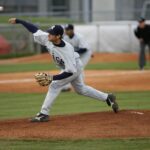 A baseball pitcher on the mound, throwing an overhand pitch.
