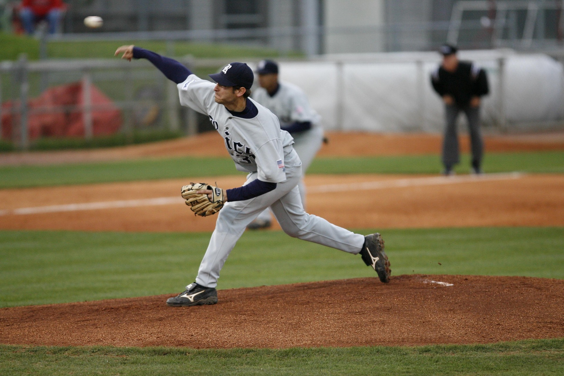 A baseball pitcher on the mound, throwing an overhand pitch.