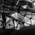 A baseball player at bat behind a chain link fence.