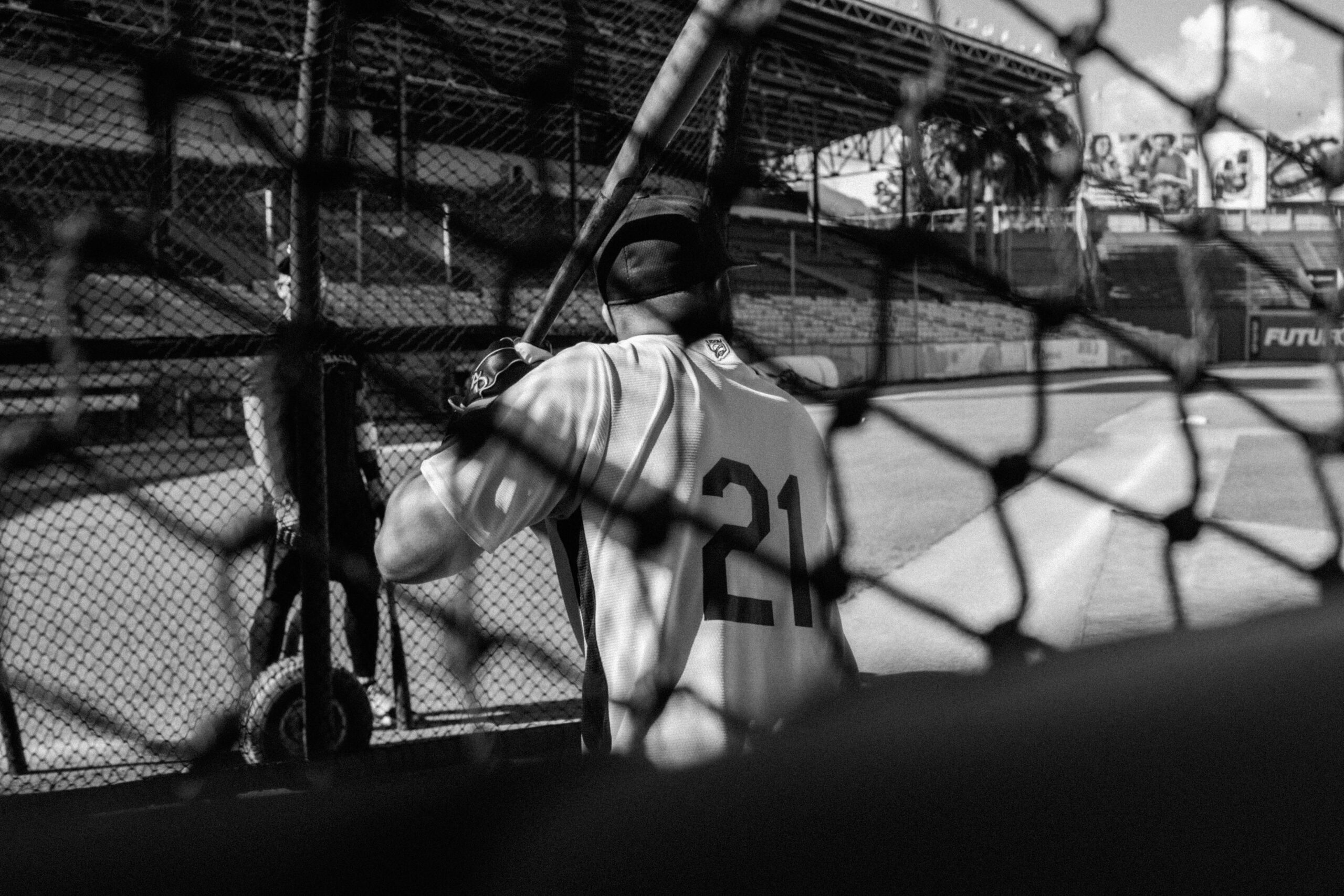 A baseball player at bat behind a chain link fence.