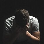 A despairing man holds his head in his hands.