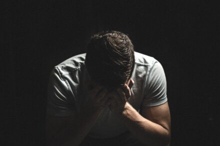 A despairing man holds his head in his hands.
