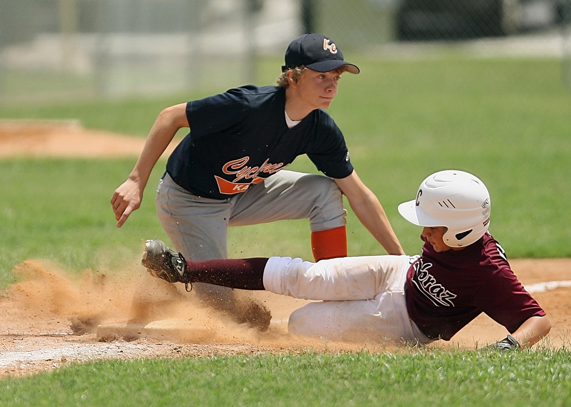 A baseball player slides into base before being tagged out.