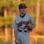 A baseball player is standing in the field with a puzzled look.
