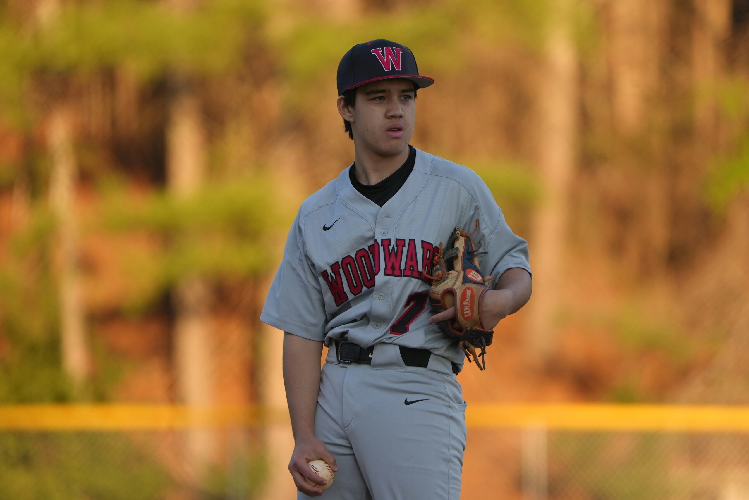 A baseball player is standing in the field with a puzzled look.