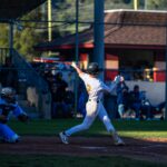A baseball player swings at a pitch at home plate.