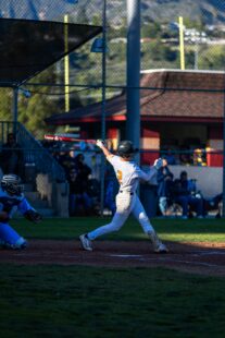 A baseball player swings at a pitch at home plate.