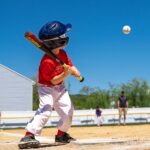A baseball player is batting at the plate, watching the ball come toward him.