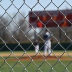 A chain link fence partially obscures the view of a baseball field.