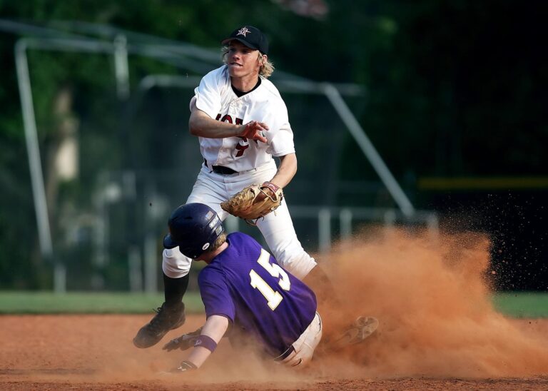 A baseball player slides into base in a cloud of dust.