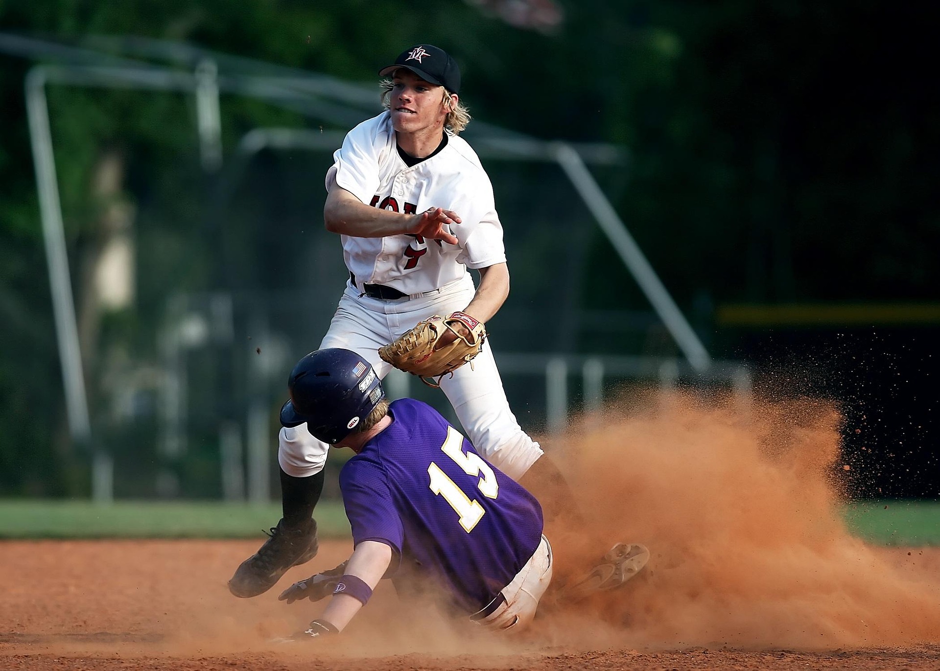 A baseball player slides into base in a cloud of dust.