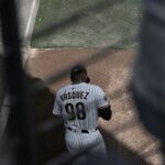 A baseball player is walking and looking down.