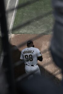 A baseball player is walking and looking down.