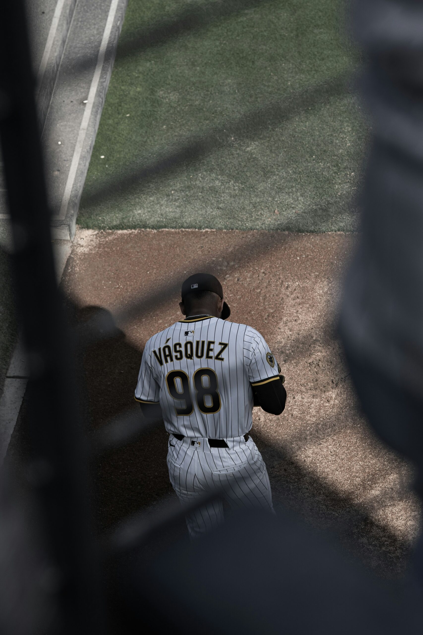A baseball player is walking and looking down.