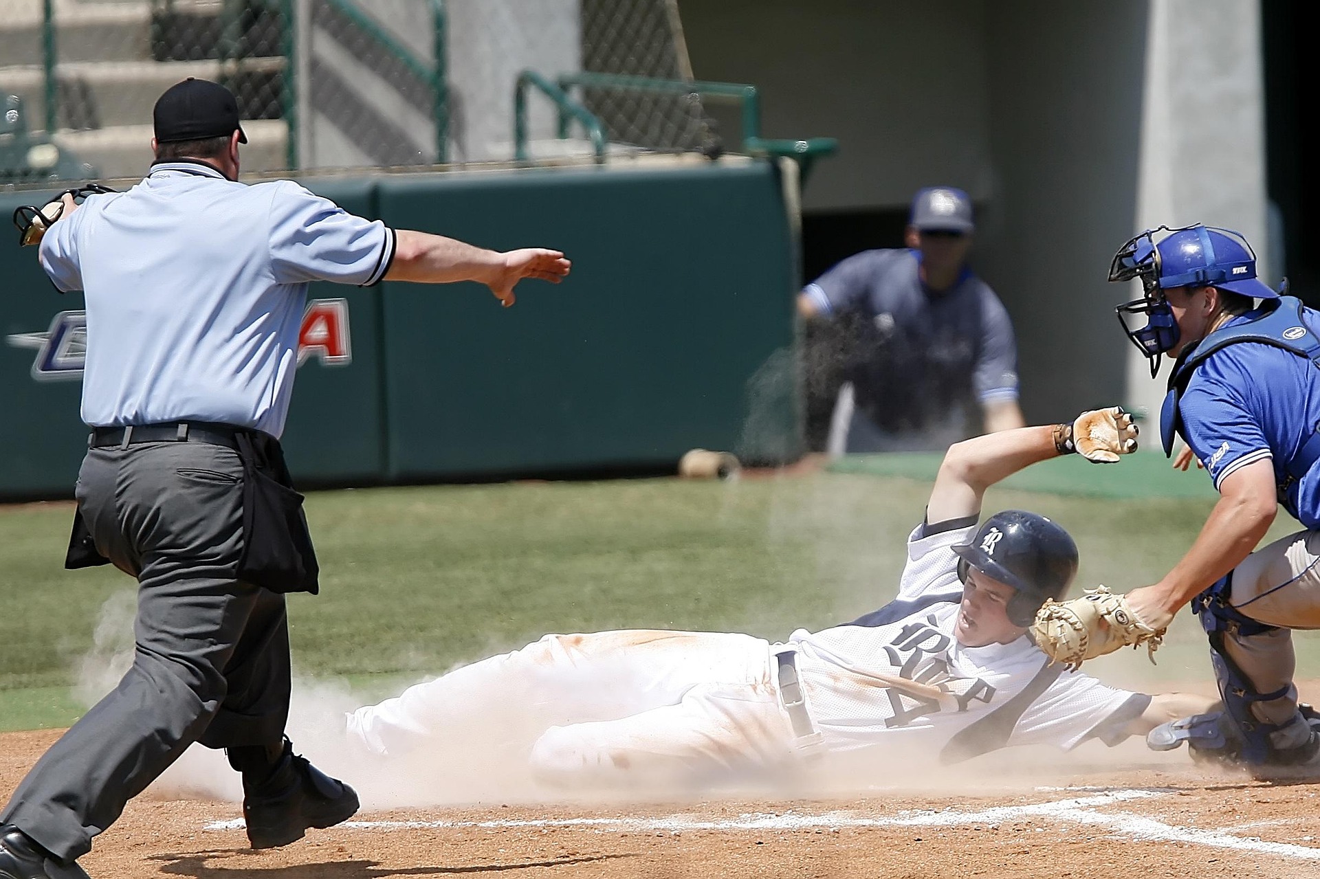 A base runner slides into place while the umpire gestures at him.