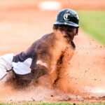 A baseball player slides into base amidst a cloud of dust.