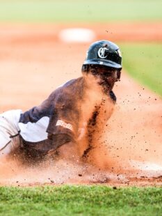 A baseball player slides into base amidst a cloud of dust.