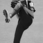A baseball pitcher is on the mound, winding up for the pitch.