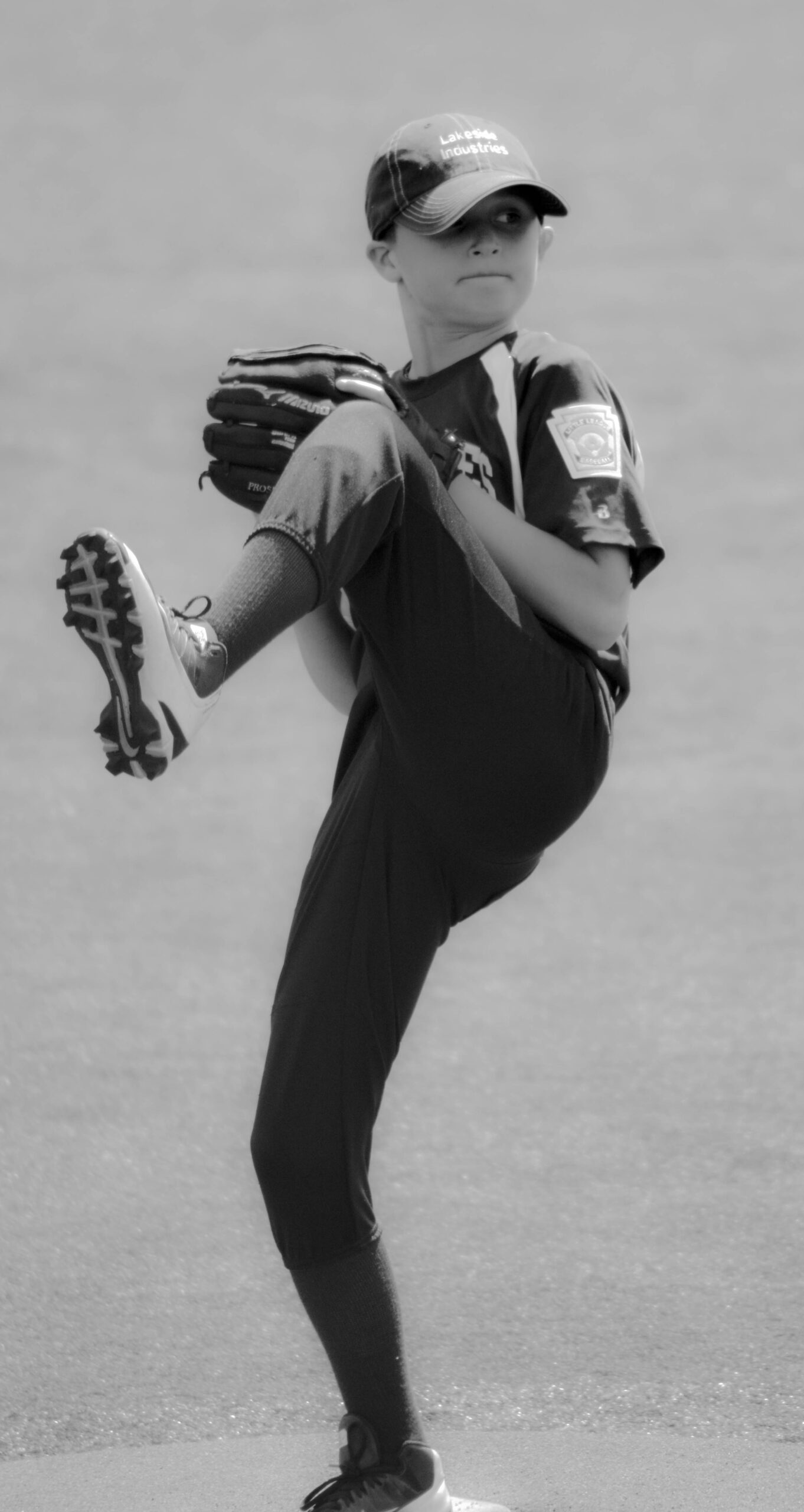 A baseball pitcher is on the mound, winding up for the pitch.