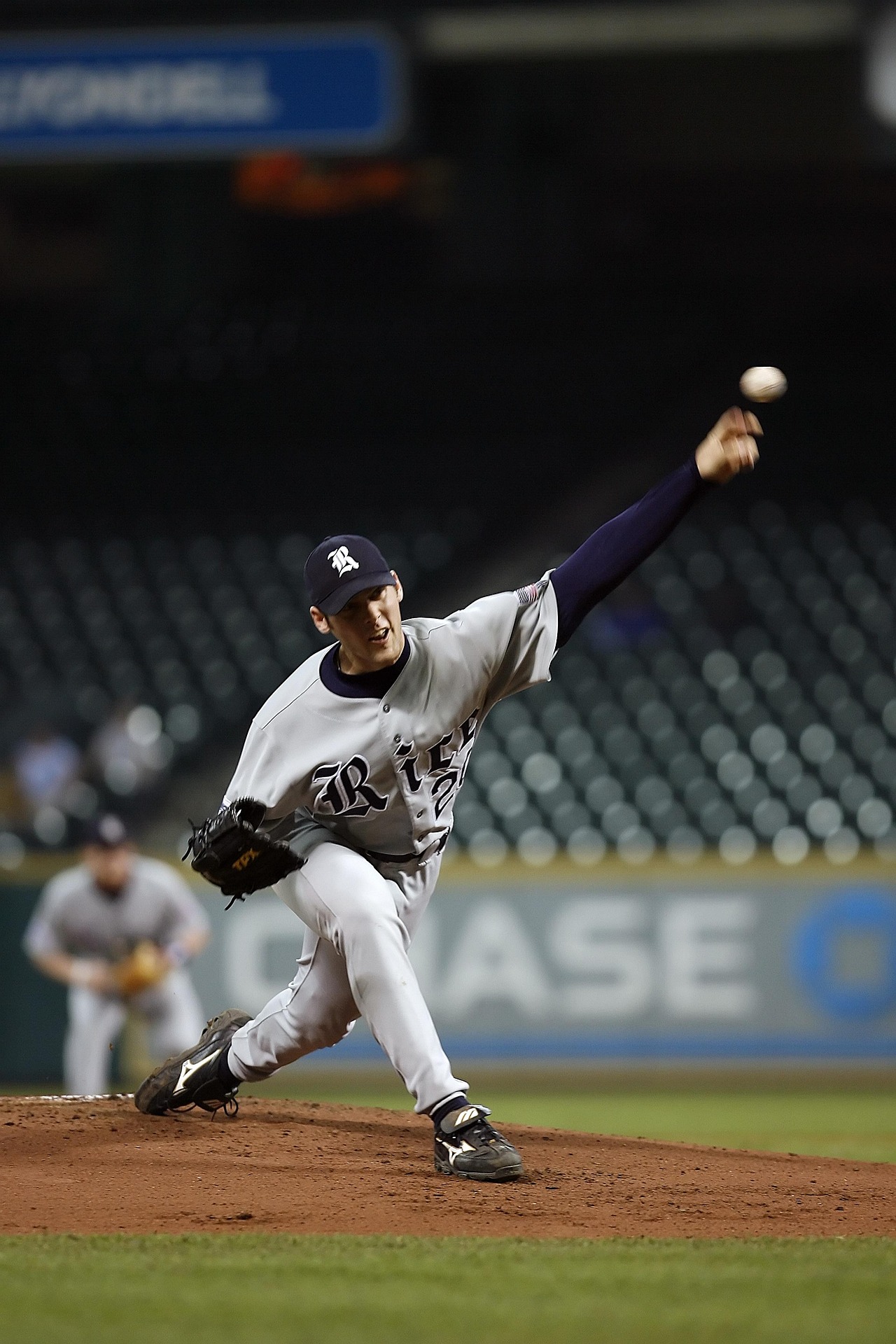 A baseball pitcher hurls a pitch toward home plate.