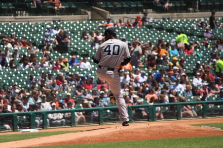 A baseball pitcher is on the mound, winding up.