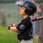 A baseball player holding hit bat looks up in anticipation.