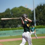 A batter holds the bat after swinging at the ball.