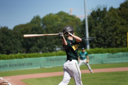 A batter holds the bat after swinging at the ball.