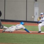A baseball player slides to the base after trying to steal.