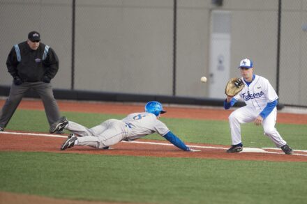 A baseball player slides to the base after trying to steal.