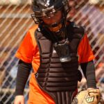 A baseball catcher looks sadly at the ground.