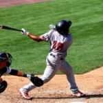 A batter lets fly and watches as the ball soars.