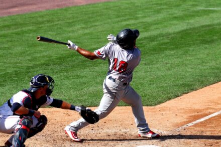 A batter lets fly and watches as the ball soars.