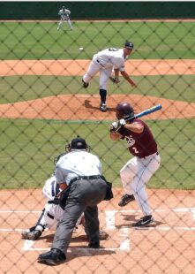 A pitcher throws the ball at the batter, with the catcher and umpire behind him.