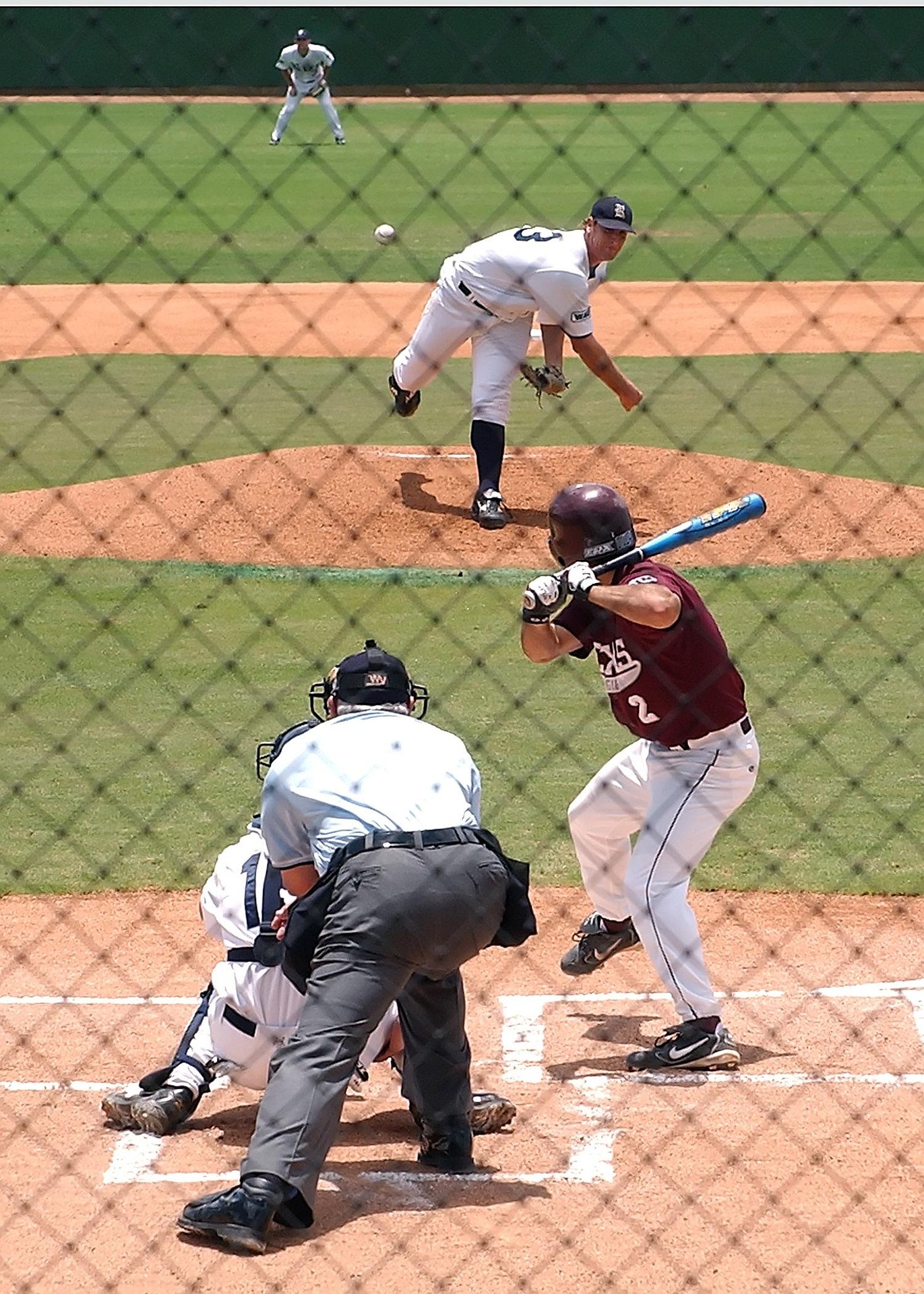 A pitcher throws the ball at the batter, with the catcher and umpire behind him.