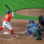 A batter at home plate is ready to swing, while the catcher and umpire look on.