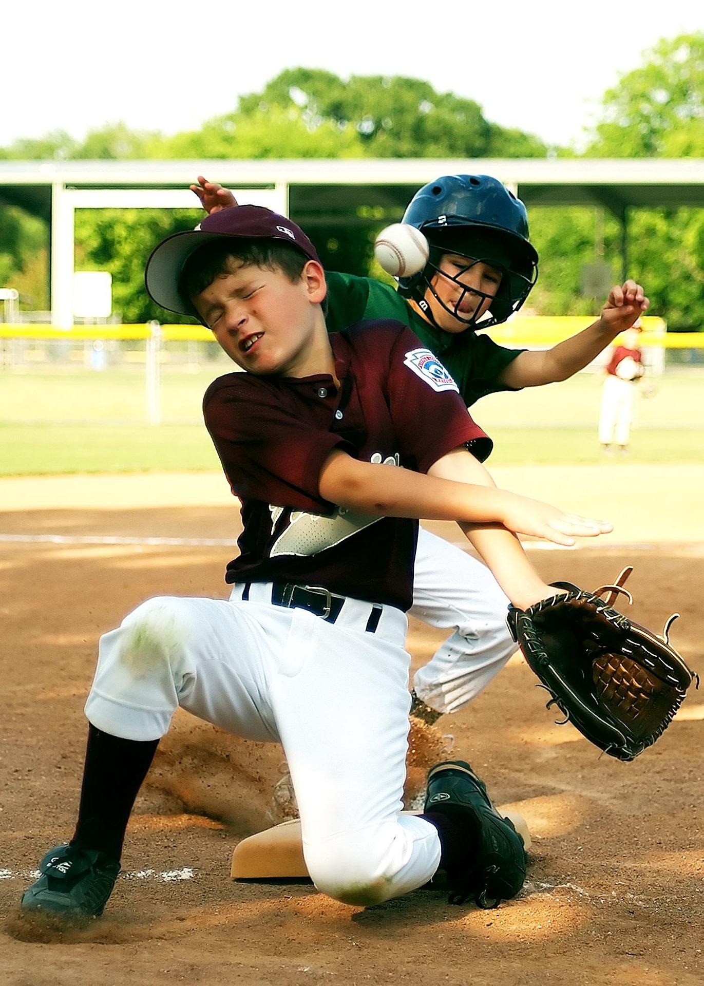Two baseball players and the ball collide on base.