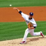 A pitcher on the mound throws the baseball toward home plate.