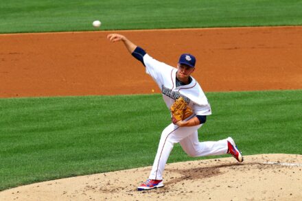 A pitcher on the mound throws the baseball toward home plate.