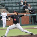 A baseball pitcher pulls back before releasing the pitch.