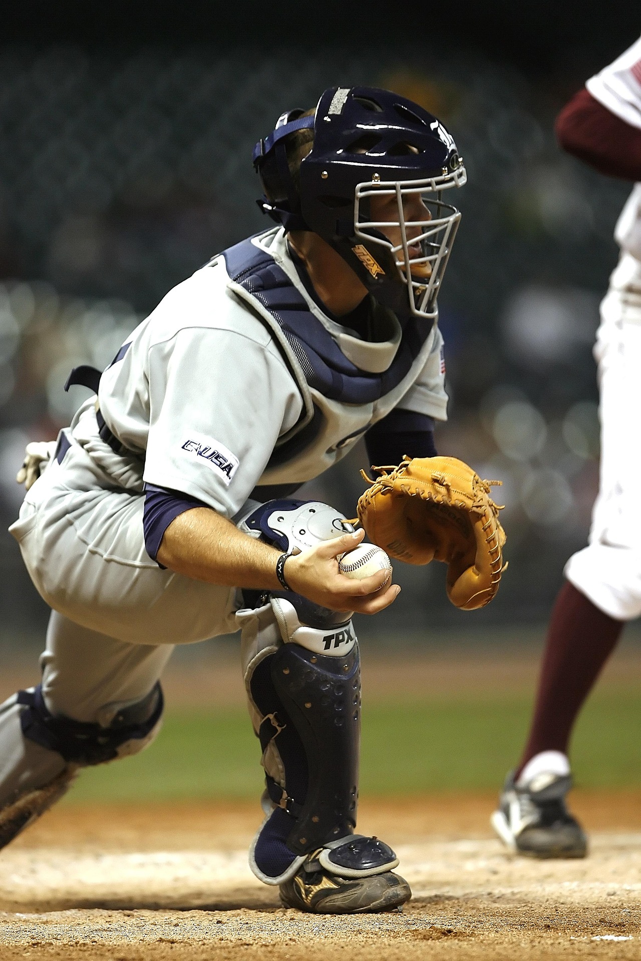 A catcher leans forward to catch the ball.