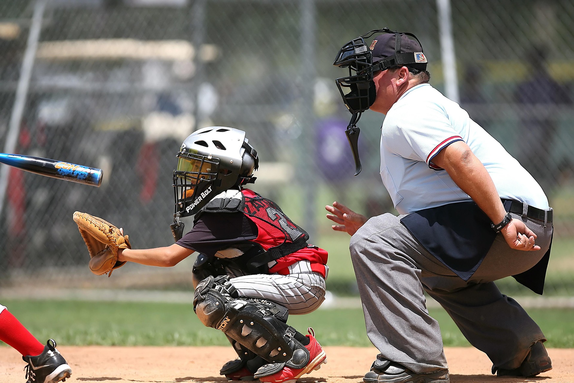The catcher is crouched behind home plate, with the umpire looking on.